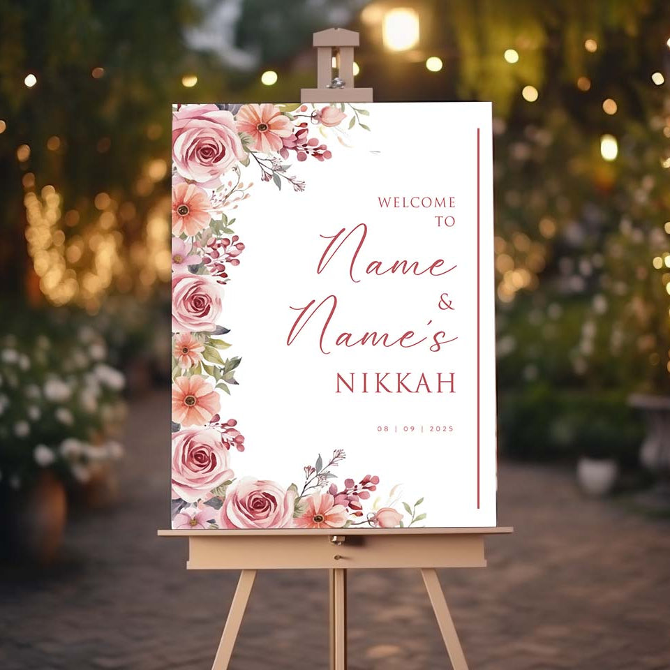 Decorative sign on an easel with floral design and text, set against a blurred outdoor background with lights.