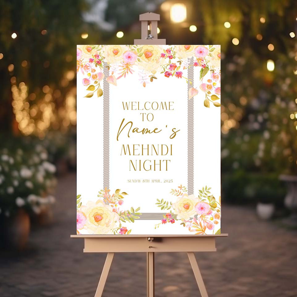 Decorative sign on an easel with floral design and text, set against a blurred outdoor background with lights.